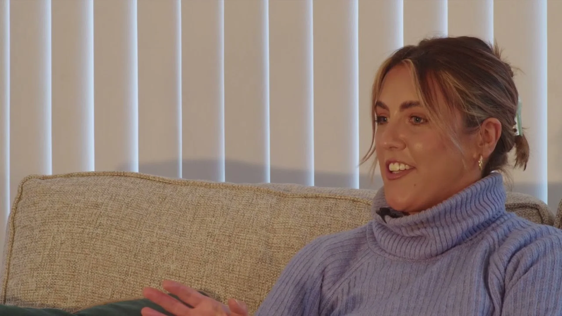 A woman in a blue turtleneck discusses brand development strategy, reflecting the Our Generation: Robert Stewart approach to creative design services.